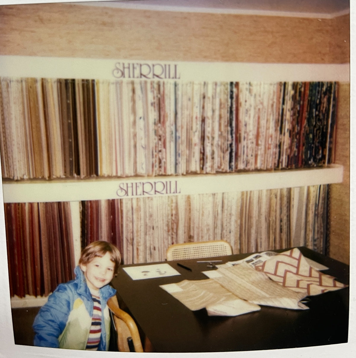 Alex Hendricks as a child among fabric samples